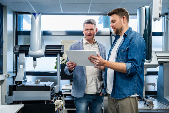 Engineers discussing project on tablet in production hall