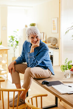 Smiling freelancer sitting on table at home office