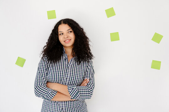 Smiling entrepreneur brainstorming with adhesive note on white wall