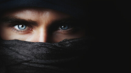 Fototapeta premium Person's striking blue eyes with an intense gaze, partially covered by a black scarf, creating a mysterious portrait composition