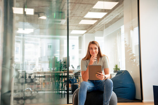 Smiling businesswoman sitting with tablet PC in office