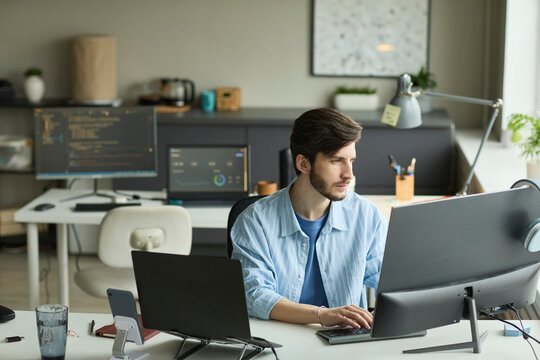 Focused software developer working on computer in modern office