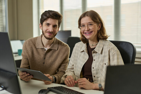 Smiling professional team with tablet in corporate office