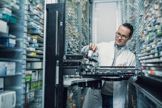 Pharmacist using an order picking machine in a pharmacy in Germany