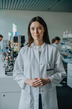 Scientist in white coat standing in laboratory with research equipment