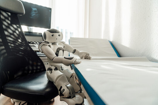 Small humanoid robot sitting in a medical examination room