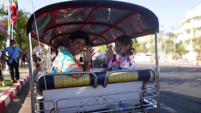 Young Asian Couple Waving from a Tuk Tuk During Songkran Festival