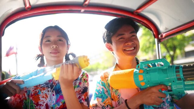 Happy Asian Couple Celebrating Songkran Festival with Water Guns in Tuk Tuk