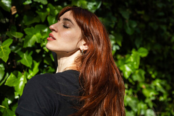 Naklejka premium Portrait of a red-haired woman on a green background.