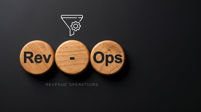 Three natural wood discs spelling RevOps with a unified funnel and gear icon above on a deep charcoal background for revenue operations strategy.