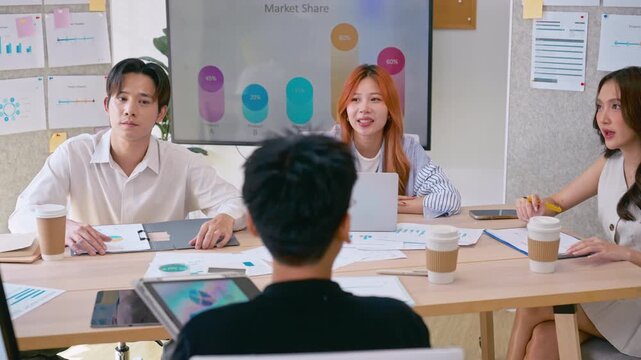 Young Asian colleagues teamwork in modern office space Discussing market trends and conducting data analysis to develop a successful business strategy together