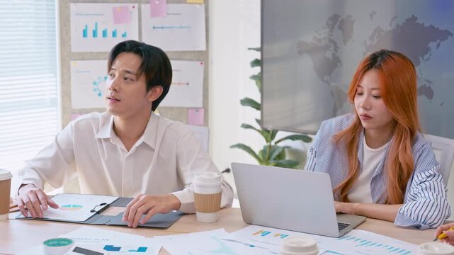 Creative young Asian business team meeting to brainstorm innovative ideas for a new venture, showing teamwork, leadership, and startup energy presentation project in a modern office.