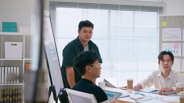 Young Asian colleagues teamwork in modern office space Discussing market trends and conducting data analysis to develop a successful business strategy together