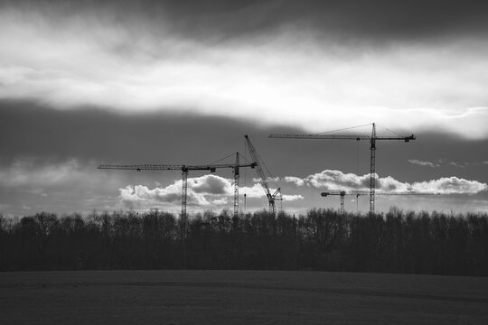 Striking Black and White Silhouette of Construction Cranes Against Stormy Sky