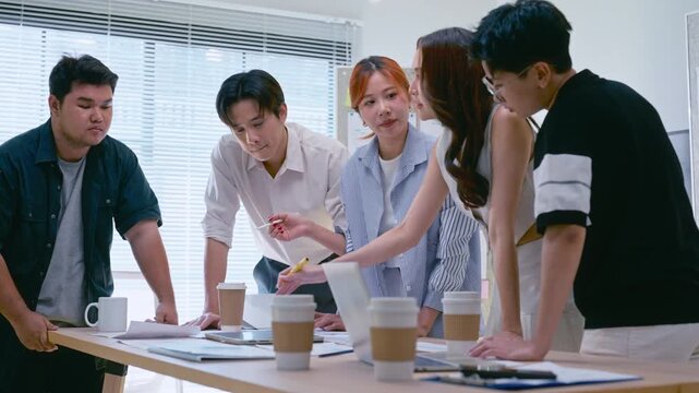 Young Asian colleagues teamwork in modern office space Discussing market trends and conducting data analysis to develop a successful business strategy together