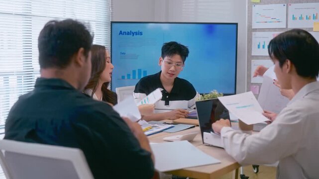 Young Asian colleagues teamwork in modern office space Discussing market trends and conducting data analysis to develop a successful business strategy together
