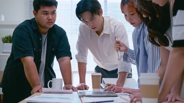 Young Asian colleagues teamwork in modern office space Discussing market trends and conducting data analysis to develop a successful business strategy together