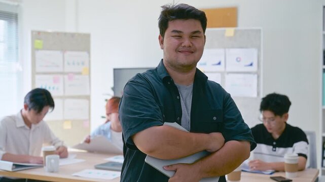 Portrait young Asian business man with team in a modern office meeting for startup seminar, teamwork, and training session, showing collaboration, professionalism, and creative business environment.