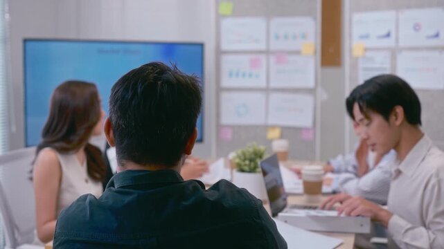 Black view Asian business boss sitting at the head of the table during a meeting. The leader is overlooking the team in a modern conference room, focused on strategy and decision making