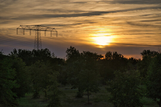 Majestic Sunset with an Electricity Pylon over a Serene Rural Landscape View
