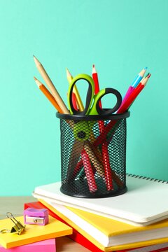 Organized office supplies in pencil holder and notebooks on desk with color background