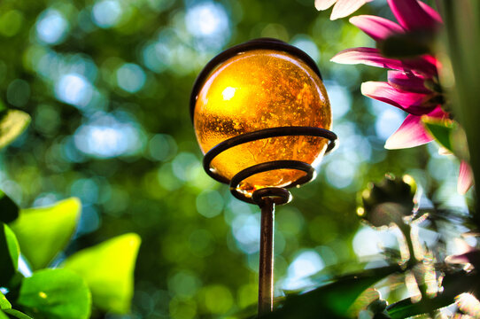 Glowing Amber Glass Garden Ornament With A Beautiful Soft Bokeh Background