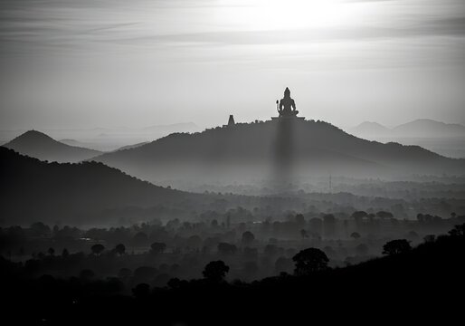 Adiyogi Shiva Statue Silhouetted on Mountain at Sunrise Over Misty Valley in Black and White