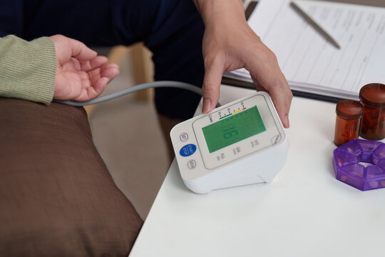 Asian healthcare professional reading digital blood pressure monitor