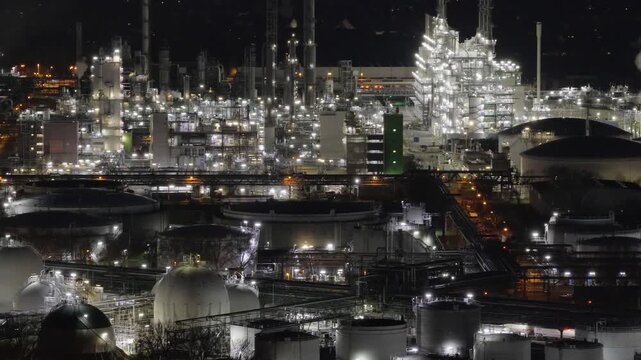 Aerial view of the sprawling BASF industrial complex at night, illuminated by countless bright lights, creating a stark contrast against the dark sky, Ludwigshafen am Rhein, Rheinland-Pfalz, Germany.