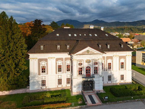 Aerial view of the grand Mosovce manor house, its bright facade contrasting its dark roof, amidst autumn trees and green lawns, Mosovce, Zilina Region, Slovakia.