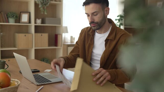 Young man paying bills online using smart phone and laptop