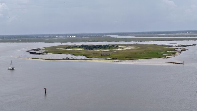 Aerial view of an island with a sandy beach surrounded by calm waters under a cloudy sky, Fernandina Beach, Florida, United States.