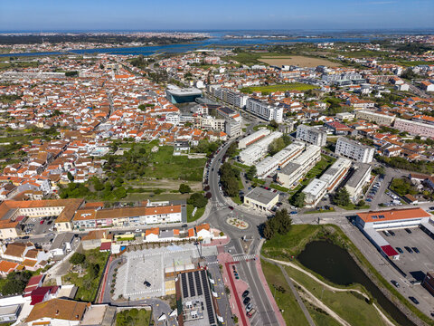 Aerial view of terracotta rooftops contrasting with modern buildings, bisected by winding roads near the water, Aveiro, Portugal.
