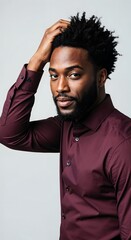 Fototapeta premium Portrait of a confident, handsome young man smiling and running his hand through his hair, wearing a stylish smart-casual tweed blazer, isolated on a white studio background.