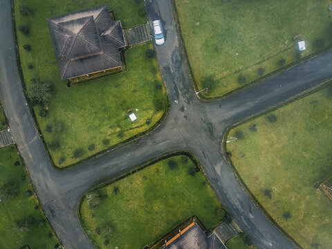 Aerial view of dark-roofed buildings nestled amidst vibrant green lawns and winding wet asphalt roads, Obudu, Cross River, Nigeria.
