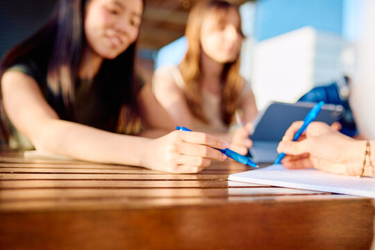 Young students working together at a table, discussing and writing notes for a group assignment while studying
