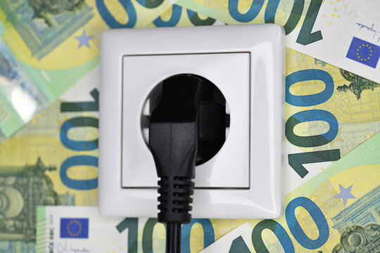 Strompreis, 100-Euro-Scheine an einer Steckdose 