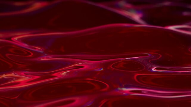 Slow motion close up of glossy red liquid surface rippling with shimmering reflections on dark studio tabletop minimal abstract texture