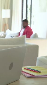 Vertical video: Leaning woman speaking and guiding boy writing homework with pencil at home table