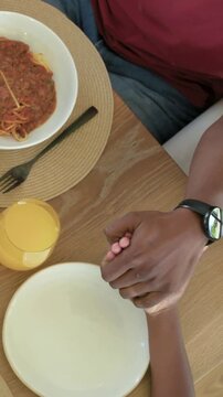 Vertical video: Holding hands dad in red tee reaching cheese, meal starting at table clearing plate