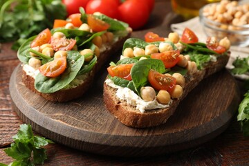 Naklejka premium Delicious sandwiches with chickpeas, cream cheese, tomato and spinach on wooden table, closeup