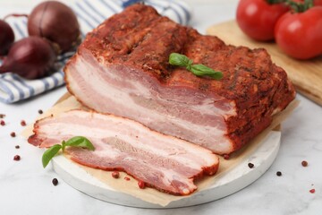 Fototapeta premium Pieces of smoked bacon, tomatoes and spices on white marble table, closeup