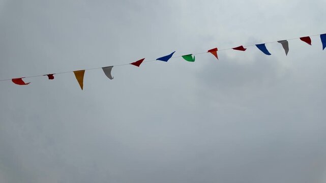 Colorful Flags Dance in Sky Festive Outdoor Celebration with Vibrant Decorations and Joyful Atmosphere Amidst Clouds