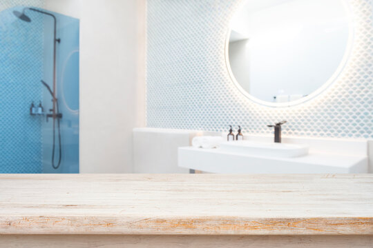 Empty wooden table top for product display with blurred modern bathroom sink and shower background