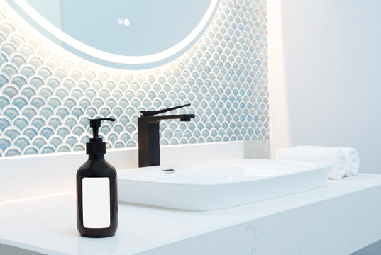 Black dispenser mockup and white high sink on stone pedestal in bathroom
