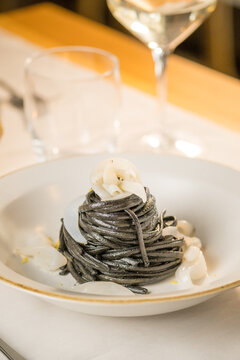 Gourmet presentation of Italian spaghetti with squid ink served on a restaurant table. 