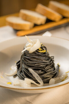 Gourmet presentation of Italian spaghetti with squid ink served on a restaurant table. 