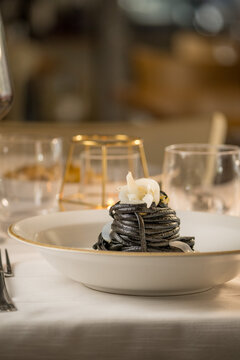 Gourmet presentation of Italian spaghetti with squid ink served on a restaurant table. 