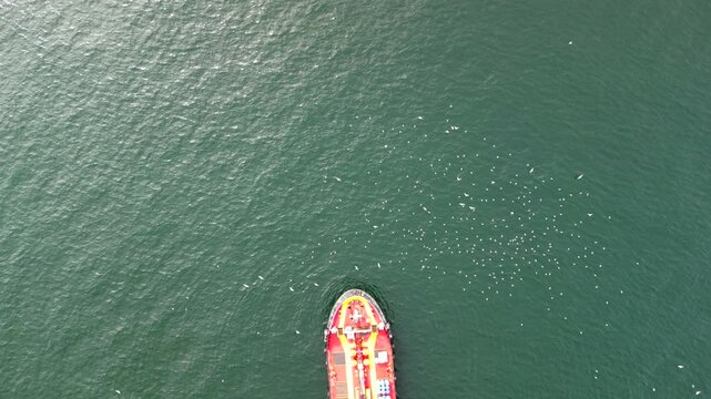 Red cargo ship slowly moving into drone shot frame