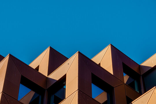 Geometric Form Architecture Shape Building Minimalist Abstract Urban Lines Exterior Featuring Sharp Angular Rooftops Symmetrical Patterns And Rhythmic Projections Under Clear Blue Sky